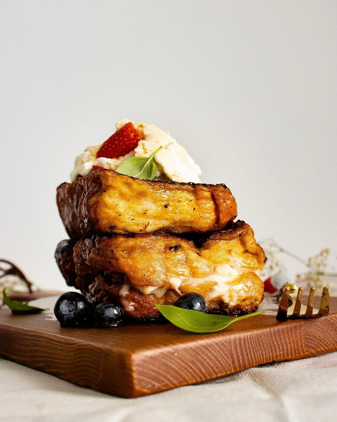 Mascarpone Stuffed French Toast stacked on a wooden board against a light grey background, no syrup pour
