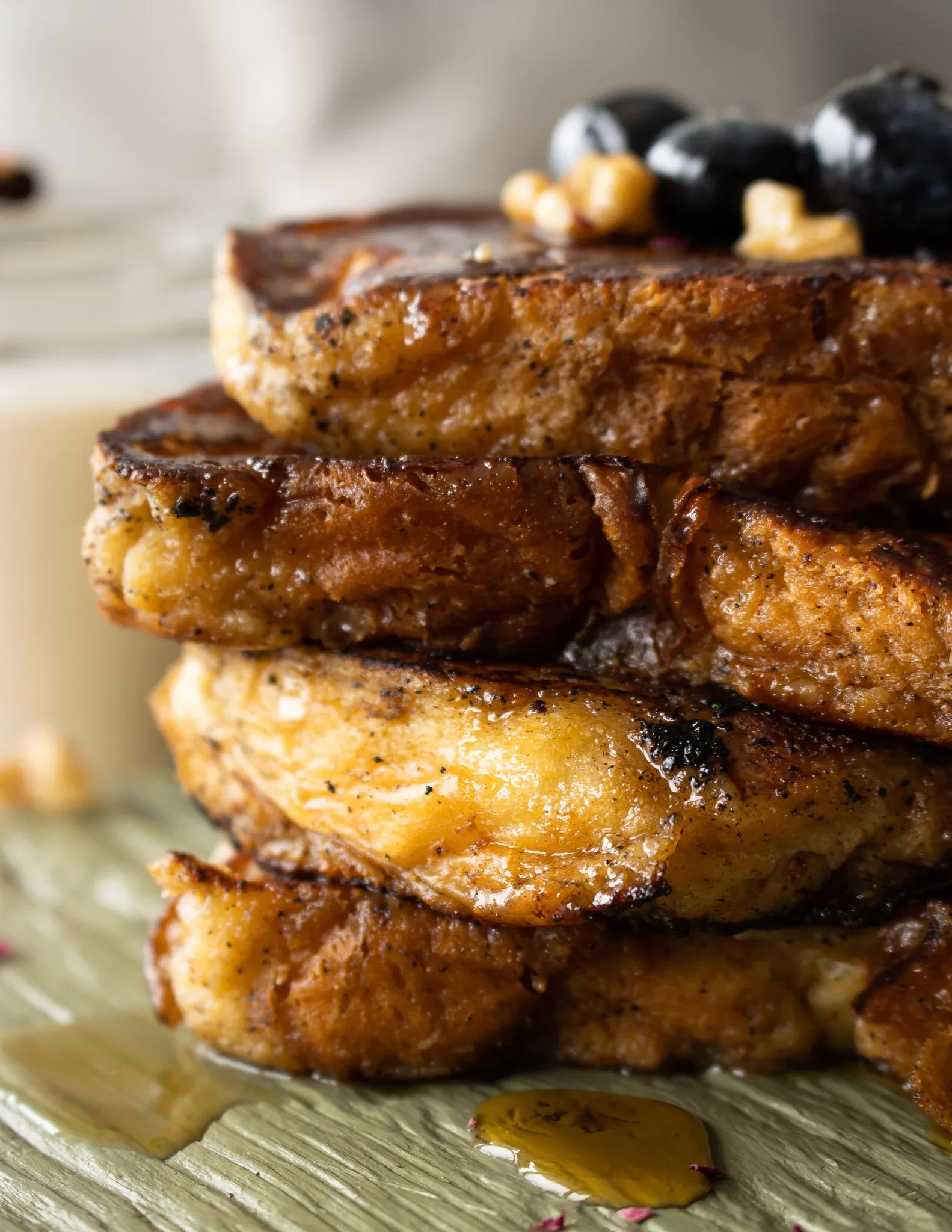 Extreme close-up macro side view of the Coquito French Toast stack showing the deeply caramelized golden-brown crust of each thick brioche slice