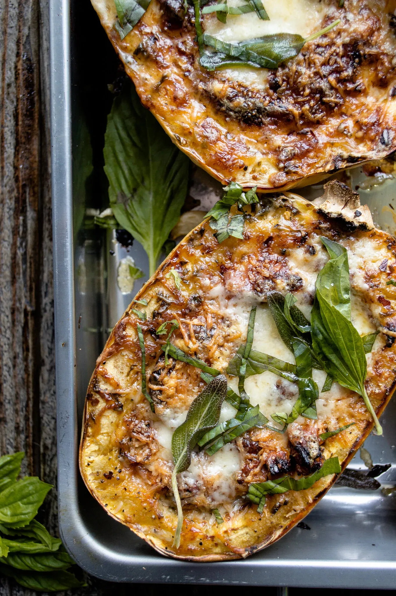 Angled close overhead view of two Stuffed Spaghetti Squash halves in a silver metal baking pan