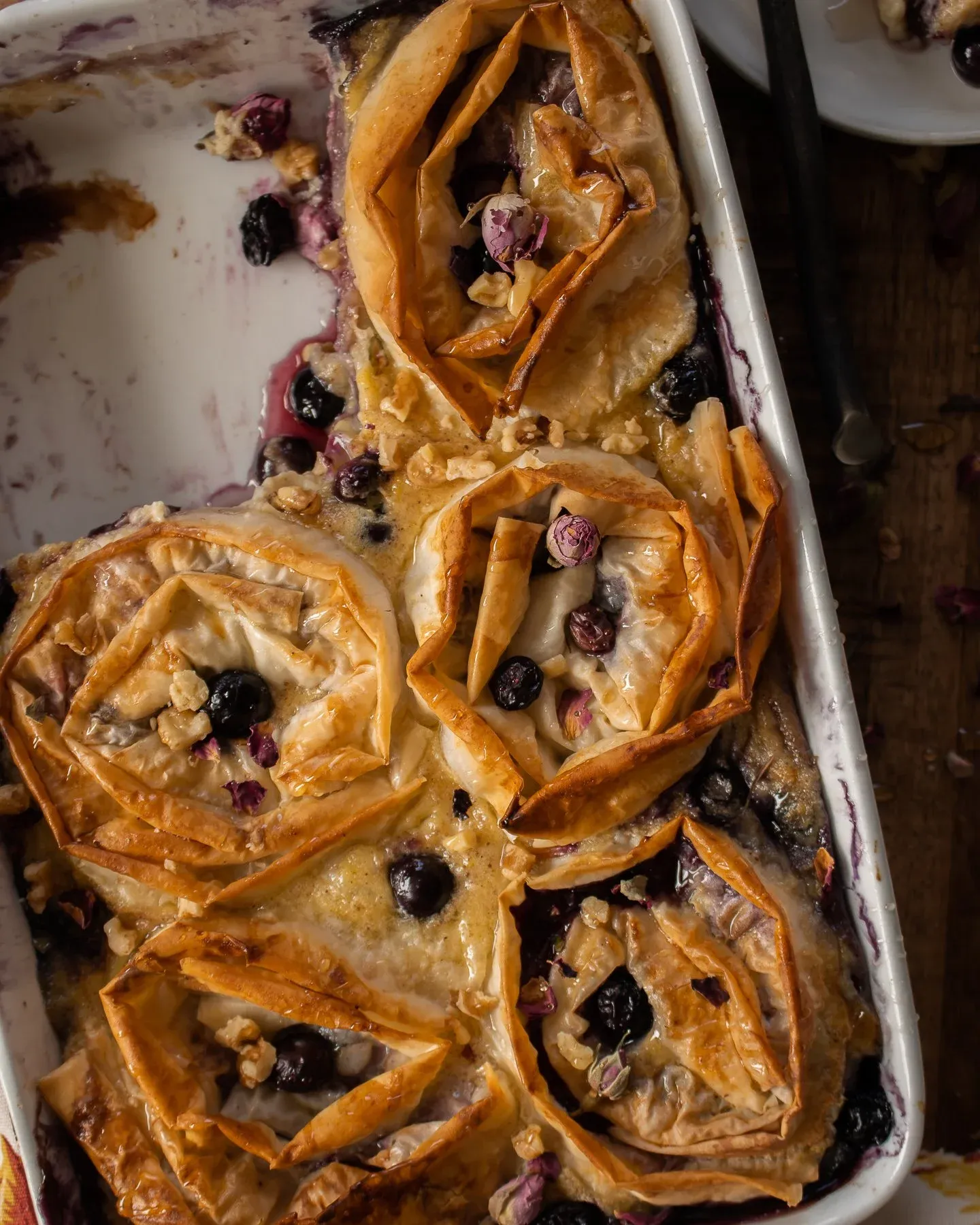 Tighter overhead angle of the Blueberry Phyllo Milk Pie showing close detail of the individual golden-brown phyllo rose-swirl portions soaking in milky custard