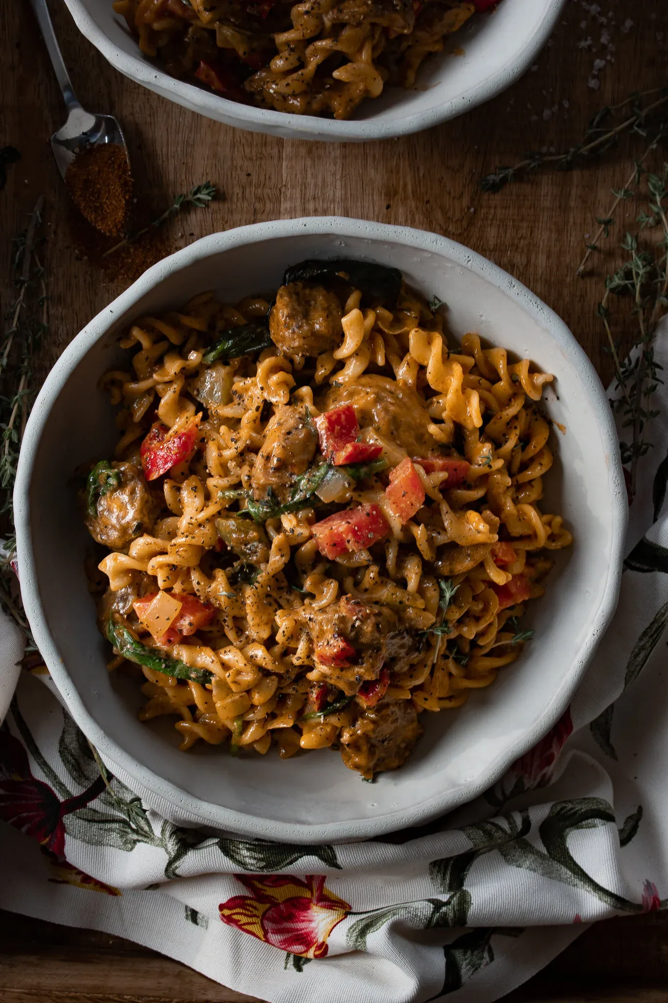 Overhead close-up of Cajun Chicken and Sausage Pasta in the white ceramic bowl under moody lighting