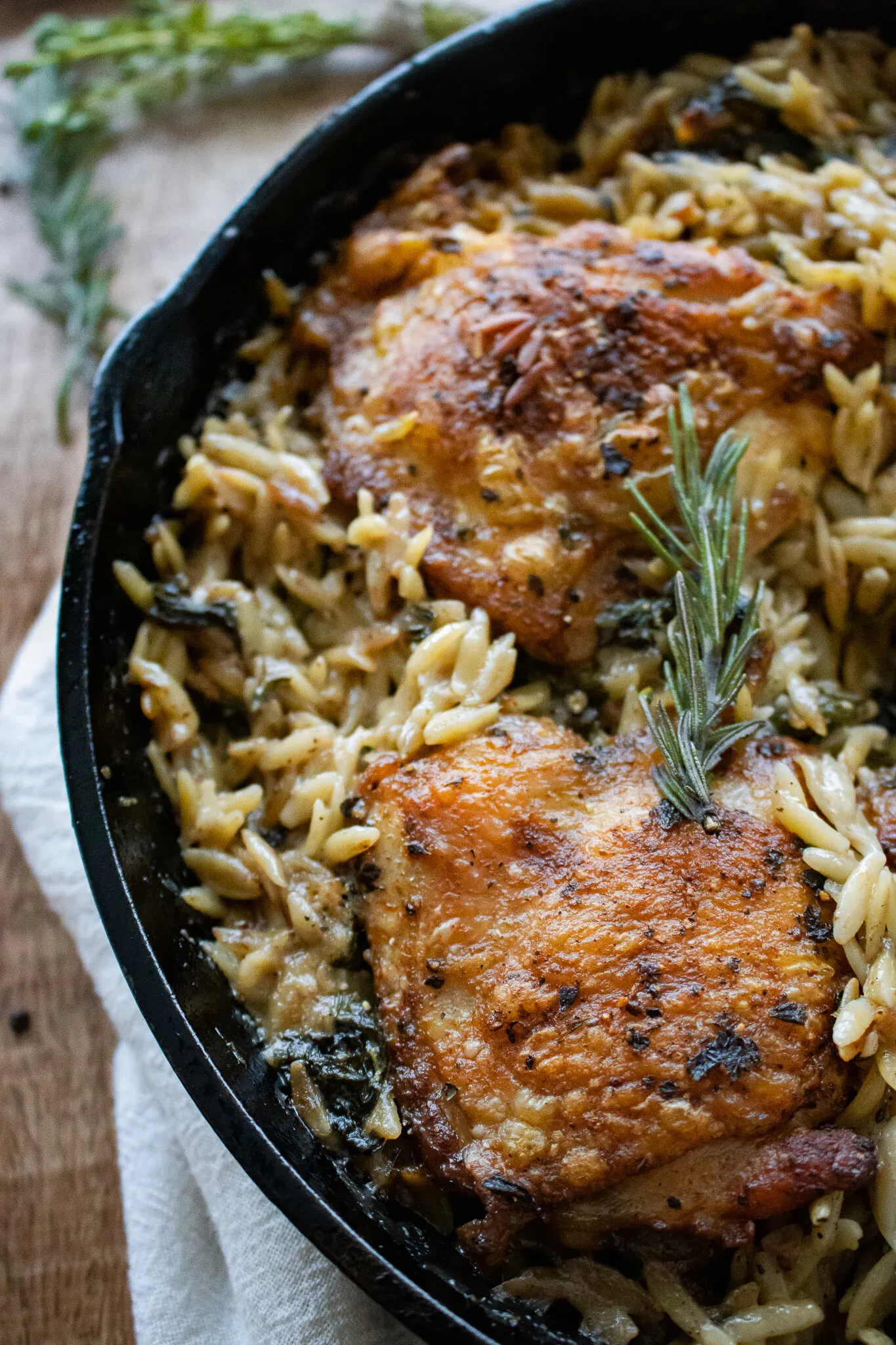 Angled close-up of two crispy golden chicken thighs in the cast iron skillet
