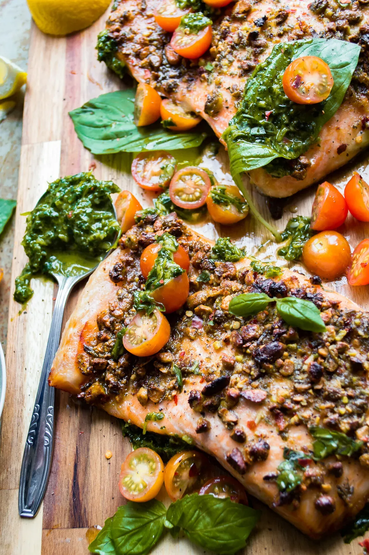 Close-up angled view of pistachio-crusted salmon fillets on a wooden board, highlighting the crunchy