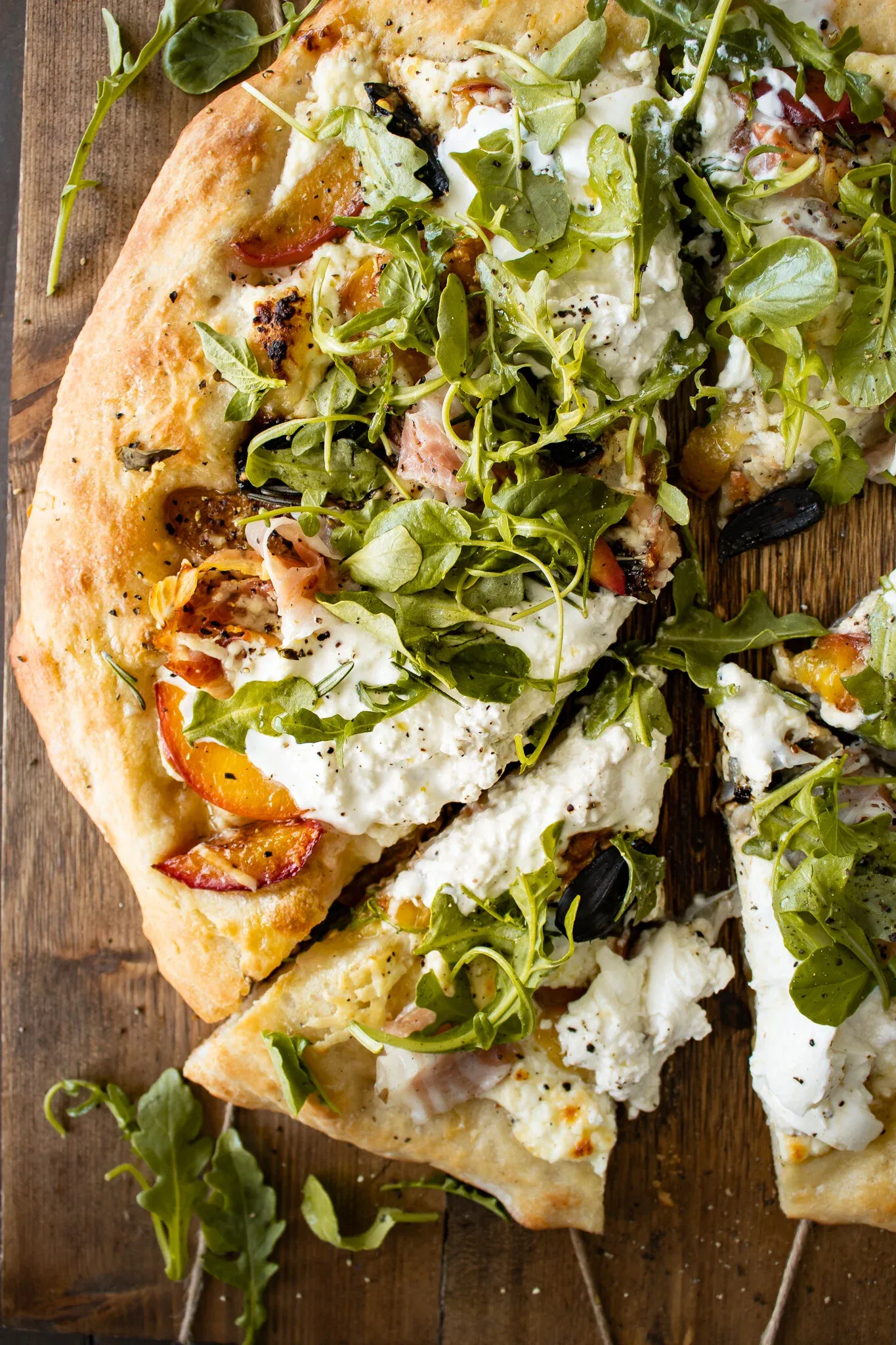 Angled close-up of sliced Burrata and Rosemary Peach Pizza with one piece slightly pulled away