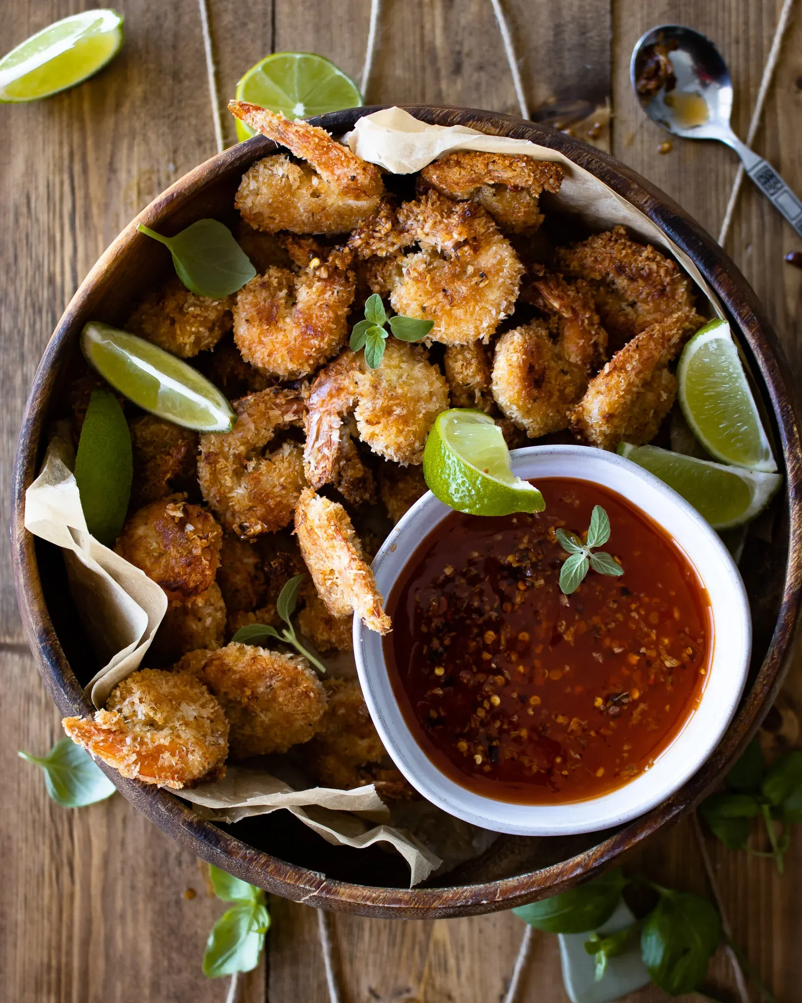 Wide overhead flat-lay of the full wooden serving bowl of Coconut Crusted Oven Fried Shrimp on a light wood-and-linen surface