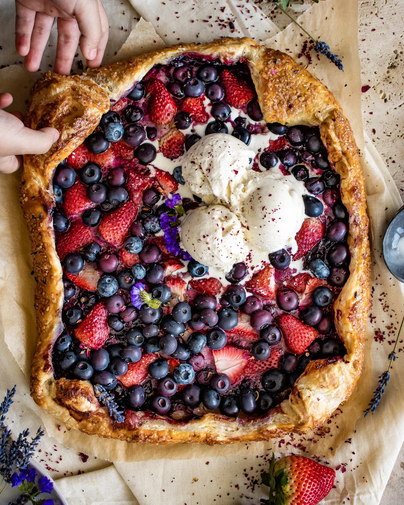 Wide overhead shot of the puff pastry berry galette with two scoops of vanilla ice cream dusted red