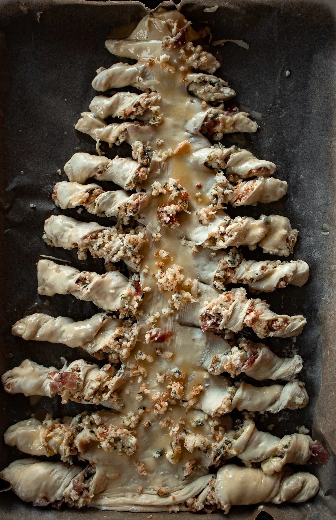 Unbaked Christmas Tree Pull Apart Bread assembled in a dark metal sheet pan