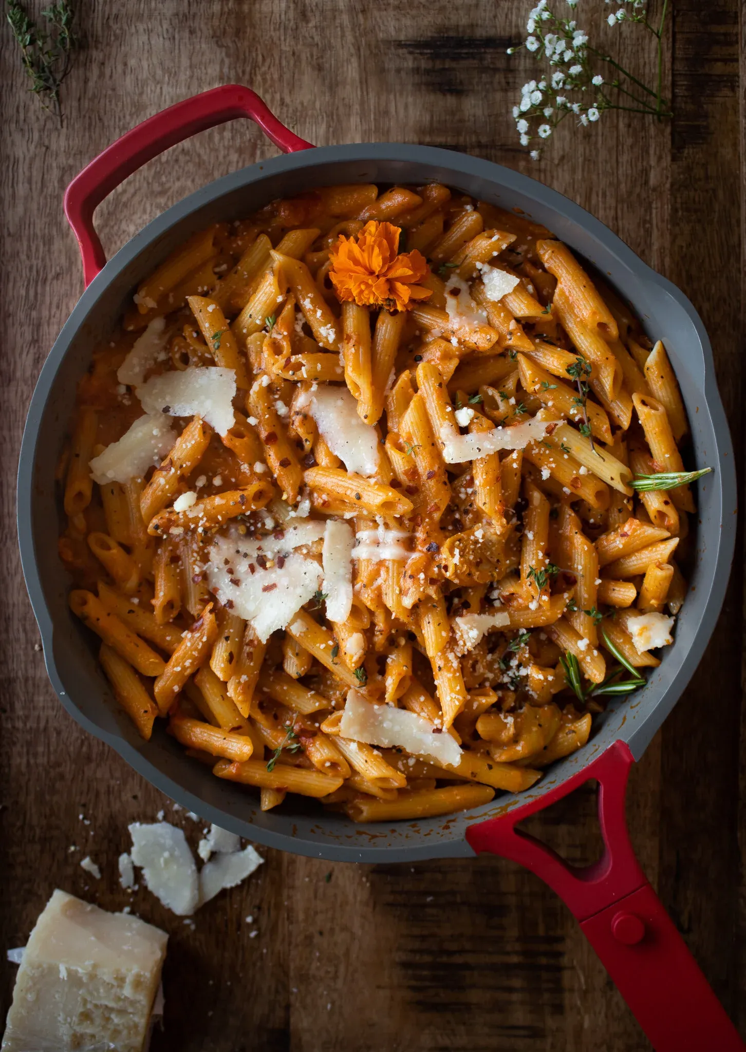 Overhead shot of pasta alla vodka still in the gray cooking pan with bright red handles