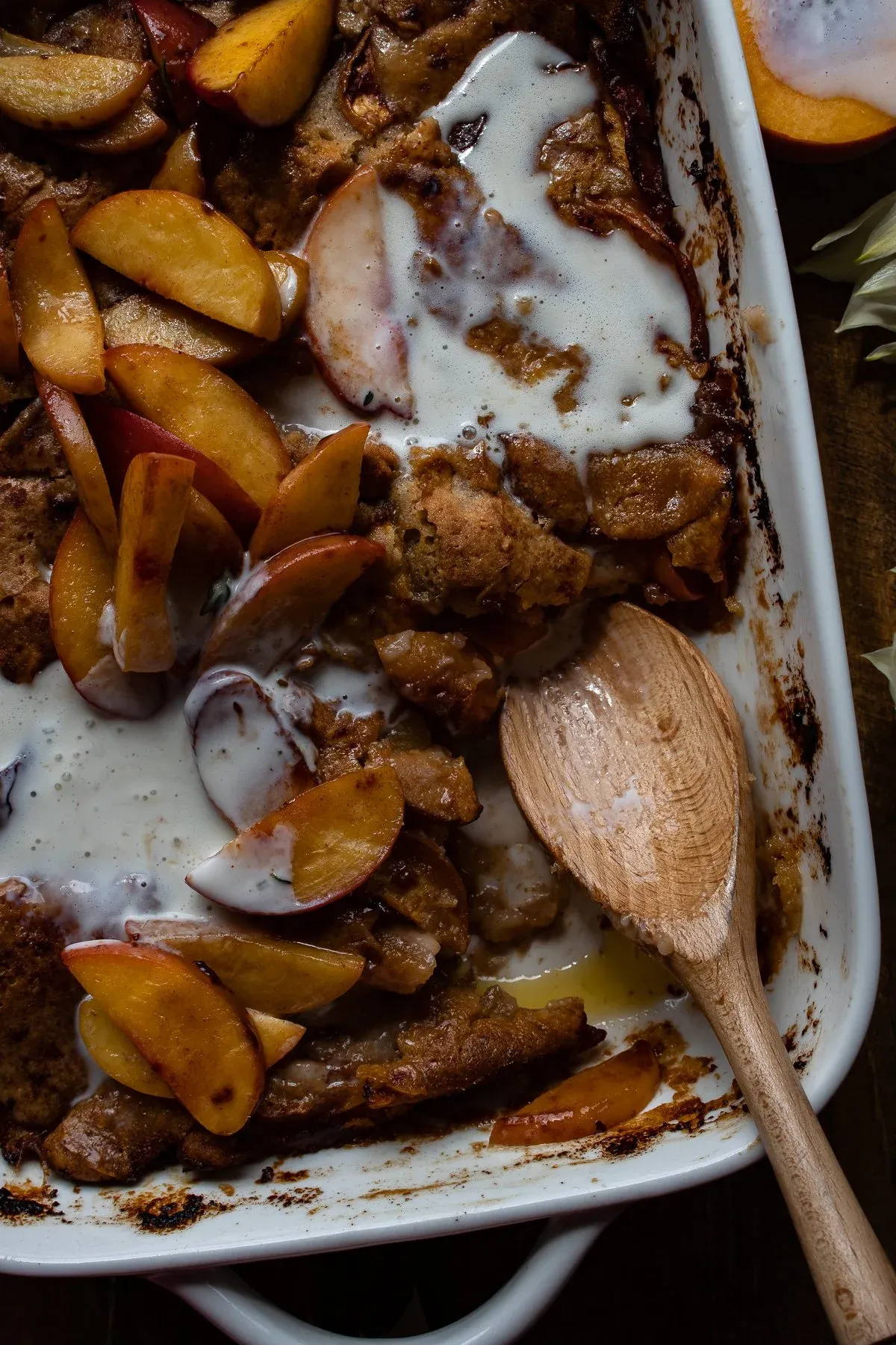 Close-up overhead of the Brown Butter Peach Cobbler baking dish after one serving removed