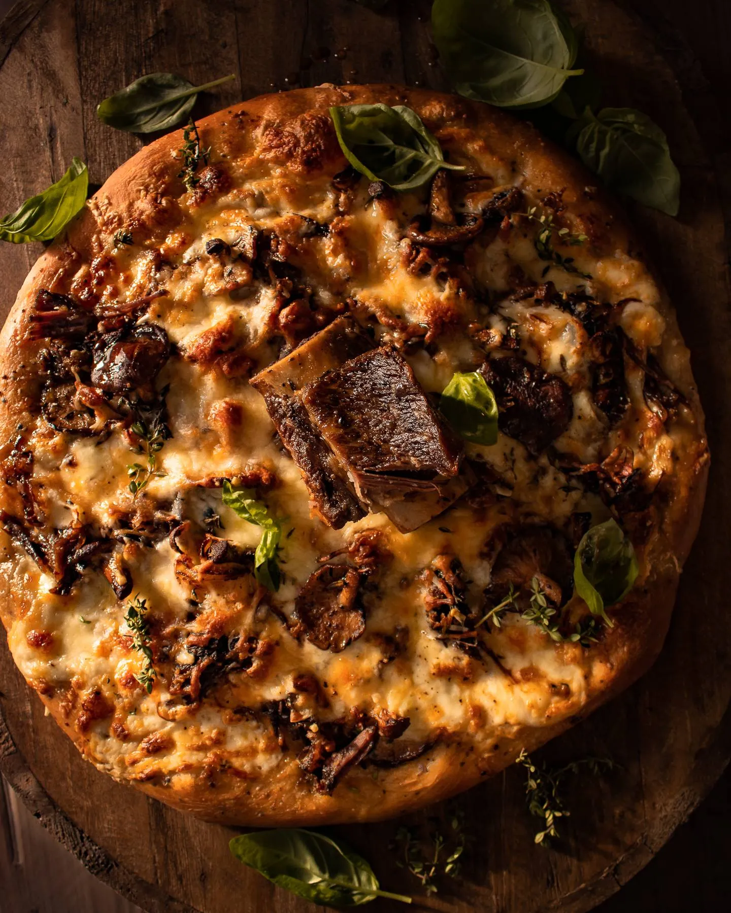 Short Rib and Mushroom Pizza presented whole on a round wooden lazy-Susan board