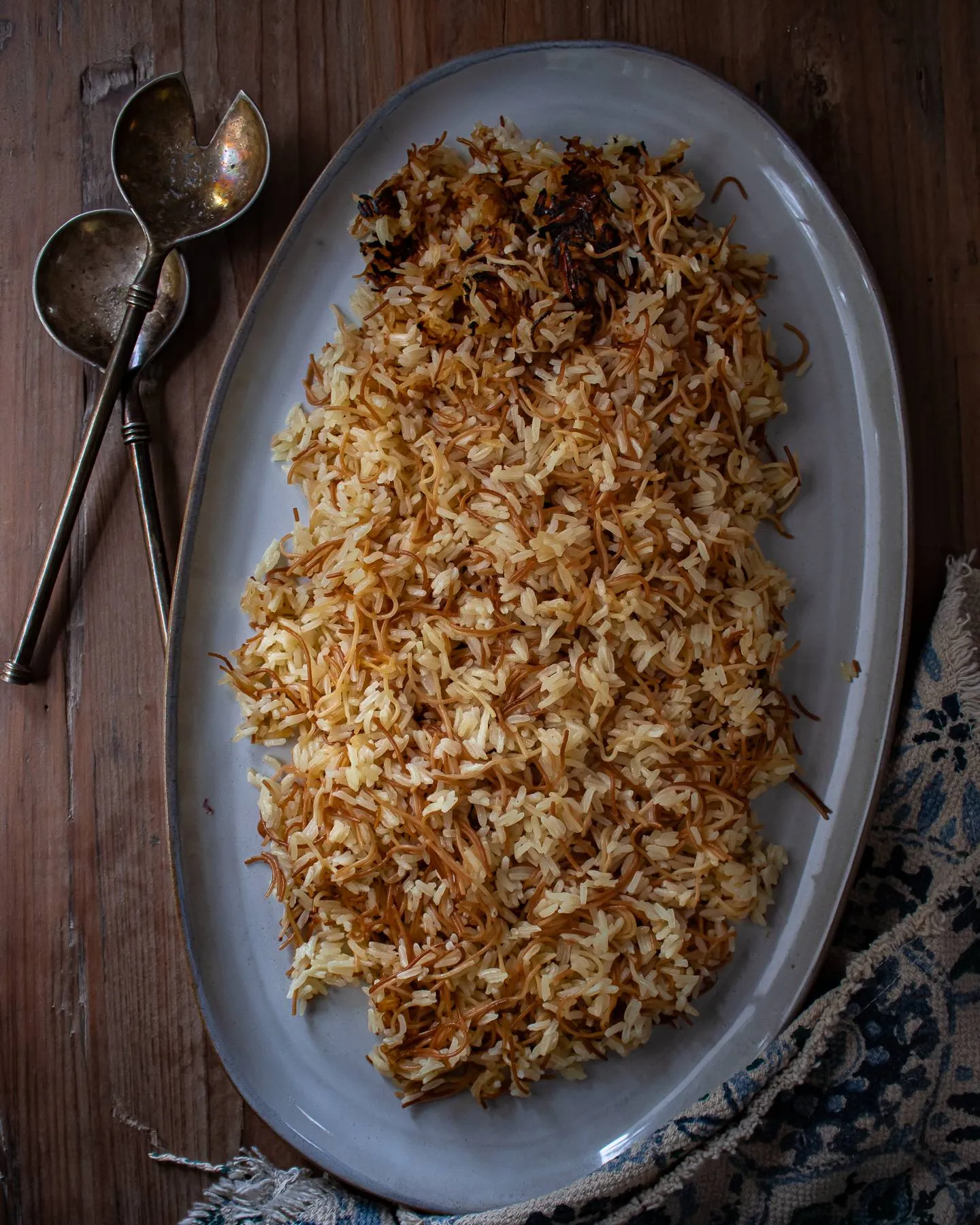 Arroz con Fideos (Dominican Rice and Fried Noodles) mounded on a grey oval platter with golden toasted fideos threaded through fluffy rice