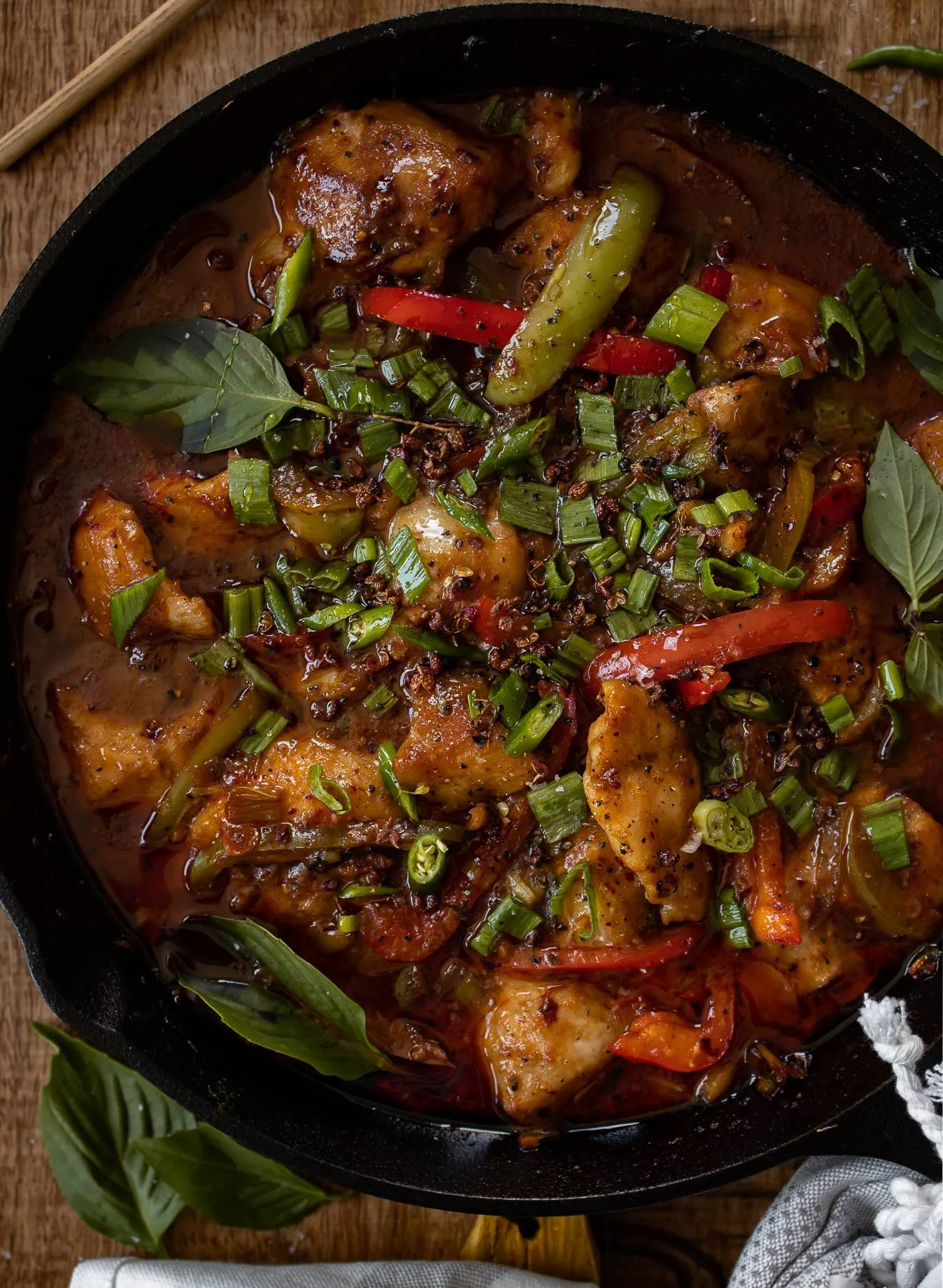 Overhead view of cast iron Asian-inspired spicy fish in a large black cast iron skillet on a dark wooden surface