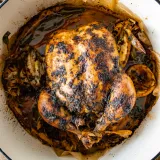 Whole Oven Roasted Chicken fresh from the pan in a round white enamel roasting dish