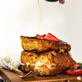 Mascarpone Stuffed French Toast stacked two slices high on a wooden cutting board