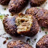 Several Dominican Quipe (Kipe) fritters clustered together on a white surface