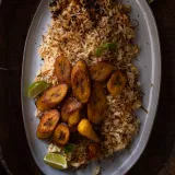 Arroz con Fideos (Dominican Rice and Fried Noodles) mounded on a grey oval platter with golden toasted fideos threaded through fluffy rice