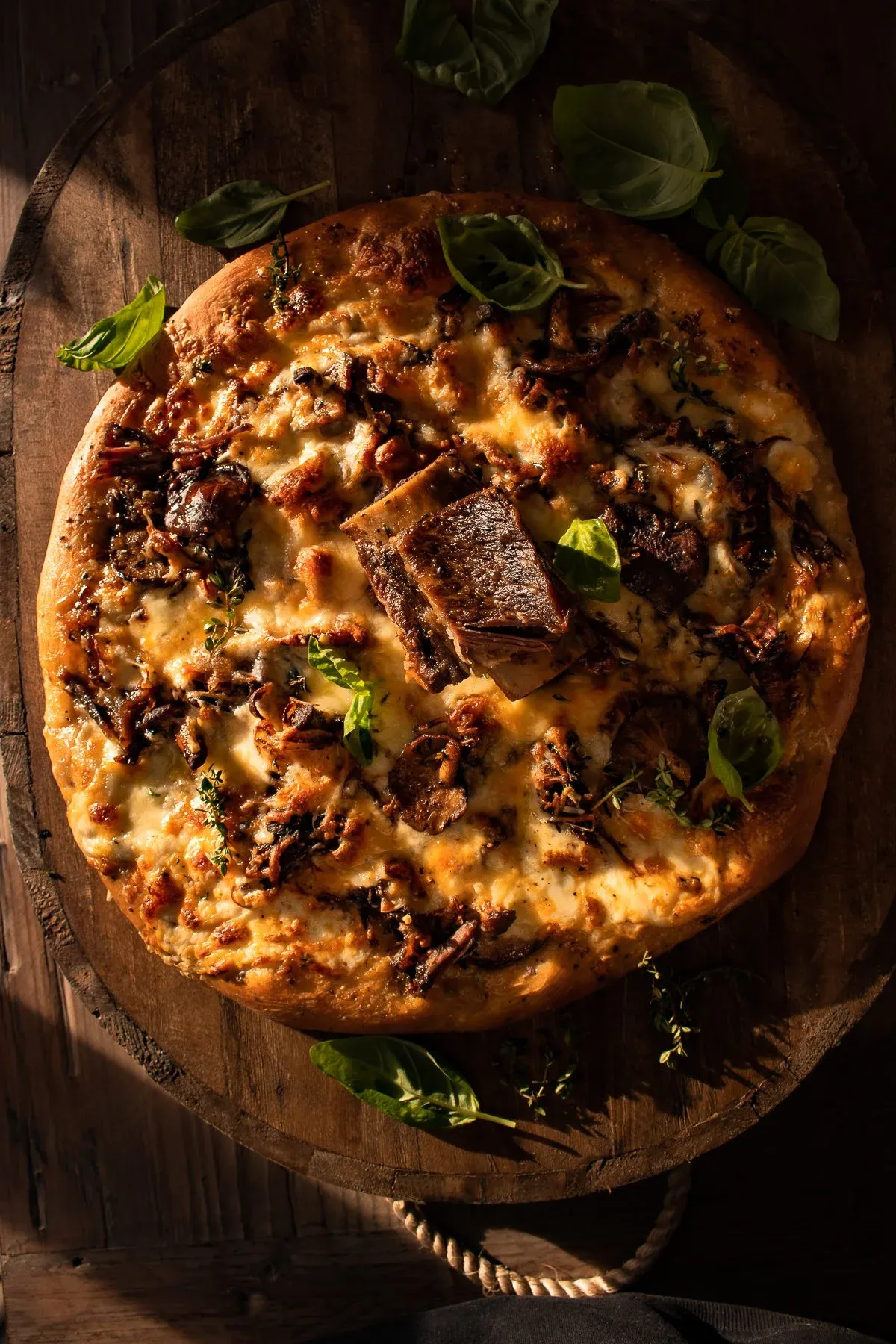 Short Rib and Mushroom Pizza presented whole on a round wooden lazy-Susan board