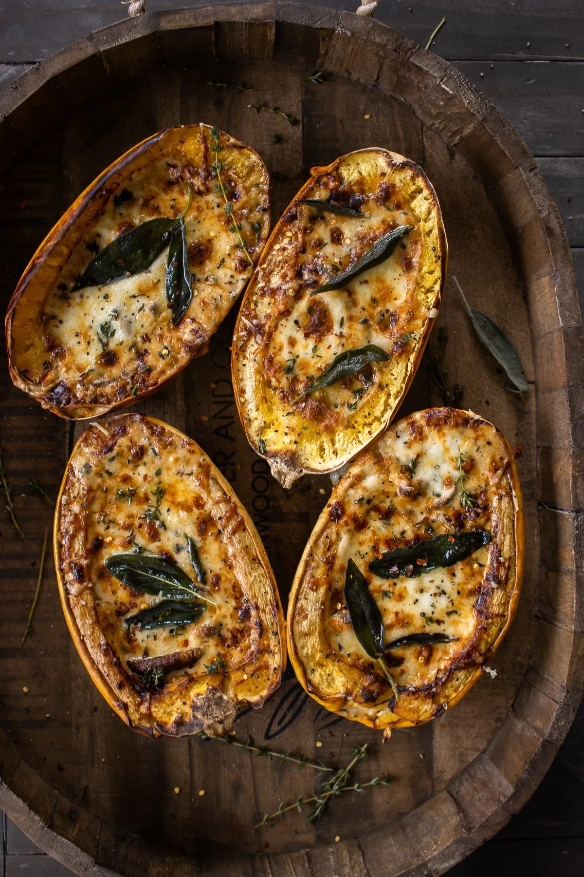 Four halved Mushroom and Sage Cream Stuffed Spaghetti Squash boats arranged on a round wooden barrel tray