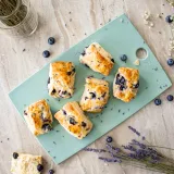 Overhead flat-lay of six golden-baked Blueberry Lavender Buttermilk Biscuits arranged on a mint-green cutting board
