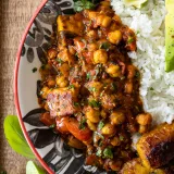 Overhead close-up of Vegetarian Chickpea and Paneer Picadillo in a decorative black-and-white floral ceramic bowl with a red rim