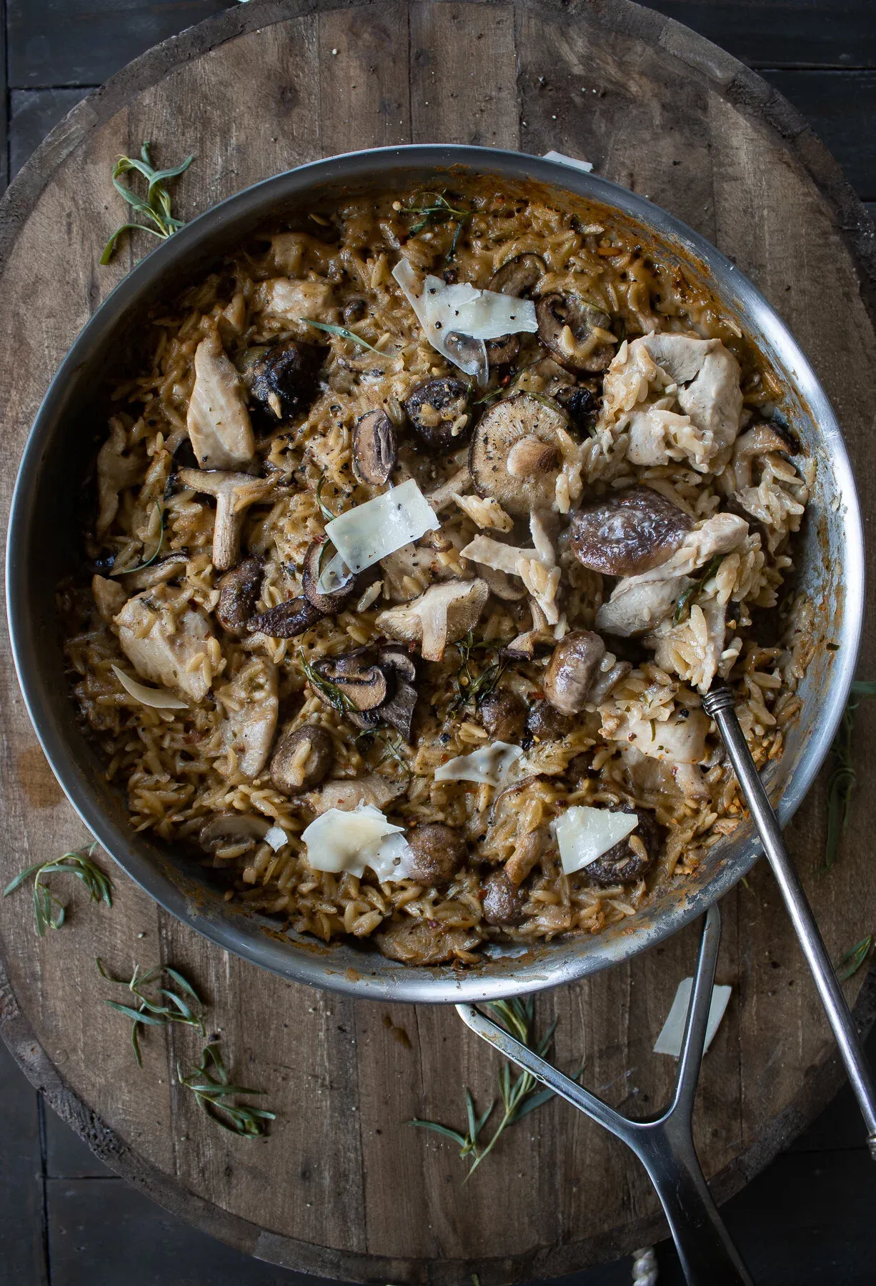One Skillet Chicken and Mushroom Orzo with Creamy Tarragon Sauce served in a large stainless steel skillet resting on a round wooden cutting board