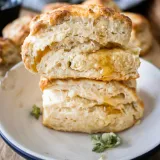 Two lemon thyme buttermilk biscuits stacked on a white enamel plate with a navy blue rim