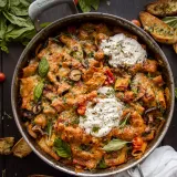Overhead view of Cheesy One-Pot Roasted Red Pepper and Tomato Pasta in a large Cuisinart stainless skillet on a dark wood surface