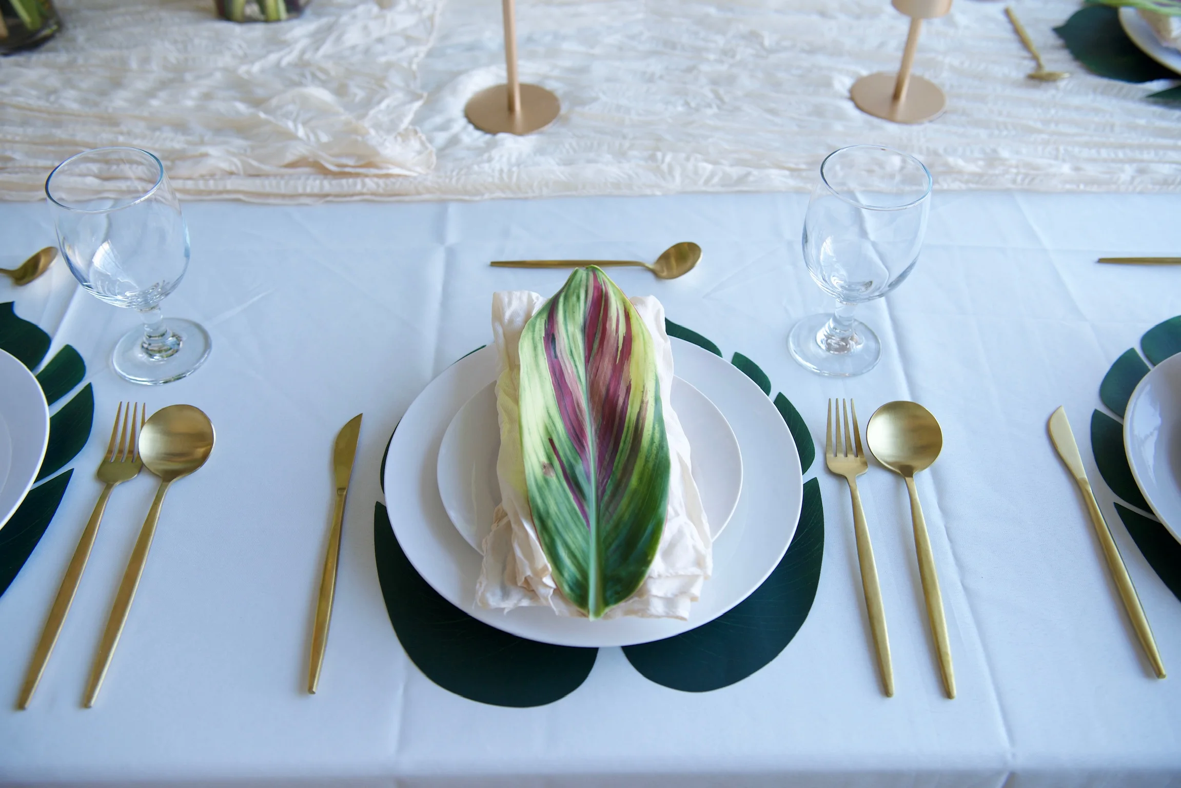 A tropical leaf place setting at a candlelit dinner table