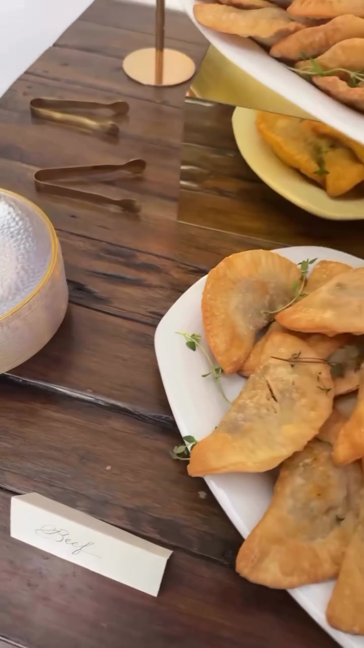 Golden empanadas laid out on a wooden table.